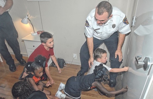 Michael Campbell, Fort Leonard Wood fire inspector, teaches children how to feel if their bedroom door is hot in the event of a house fire in the Fire Safety Trailer at a previous Fire Fest.
