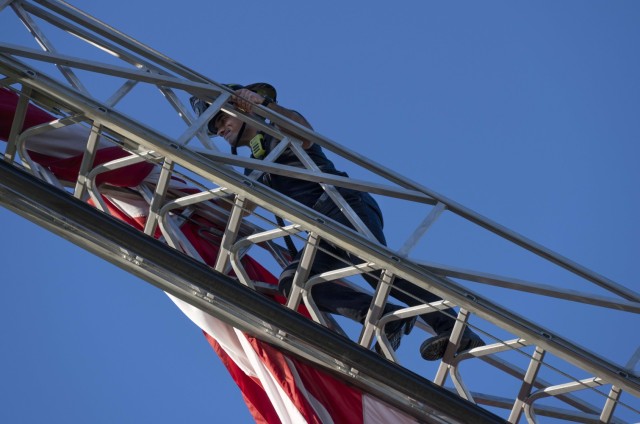 Caleb Maxwell, a firefighter with the Fort Jackson Fire Department climbs a ladder to loosen the U.S. flag that was flying above Hilton Field and the National Night Out event Oct. 4. The Fort Jackson Fire Department joined law enforcement agencies from across the Midlands for the event. 