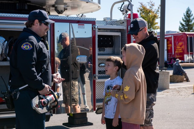 Fort Leonard Wood Firefighter George Cody talks with 1st Sgt. Kevin Linde, from Company B, 2nd Battalion, 10th Infantry Regiment, and his children Elijah and Jillian about the equipment on their ladder trucks during the 2022 Fire Fest, held Saturday in the Main Exchange parking lot. 