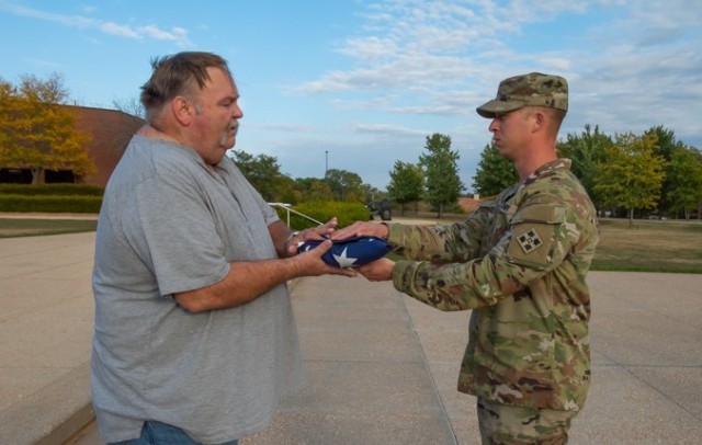 Staff Sgt. Austin Israel, NCO in charge of Fort Leonard Wood’s flag detail while he attends the Engineer Advanced Leader Course, hands Mike Siegmund his father’s internment flag after it was flown over the Maneuver Support Center of Excellence Plaza Oct. 7. Mike&#39;s father, Robert, is a World War II veteran, who completed Basic Combat Training at Fort Leonard Wood in 1943. 