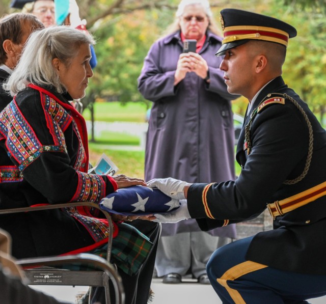 Ann Washburn Lord, the fifth great-granddaughter of Private Oliver Barrett, receives an American flag in his honor from Capt. Eric Sampson of the New York National Guard Honor Guard during military honors for the dedication of a memorial stone for Barrett at the Saratoga National Cemetery Oct. 19, 2022.  Barrett volunteered as a Minuteman and died serving under the 10th Massachusetts Regiment in the Battle of Saratoga Oct. 7, 1777, at 51 years of age.