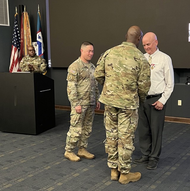 Combat Training Center Directorate Director Col. Kelvin Swint and Combined Arms Center Command Sgt. Maj. Stephen Helton watch as CAC and Fort Leavenworth Commanding General Lt. Gen. Milford Beagle Jr. presents the Civilian Service Medal and CAC CG coin to Rich Harms following the Combat Training Center Commanders Conference Oct. 19, 2022 at McHugh Training Center, Fort Leavenworth, Kan. The semi-annual conference focuses on improving training at the combat training centers. Harms was recognized ahead of his upcoming retirement for his work at CTCD with the Combat Training Center program including the planning of 28 CTC Commanders Conferences.Photo by Tisha Swart-Entwistle, Combined Arms Center-Training Public Affairs.