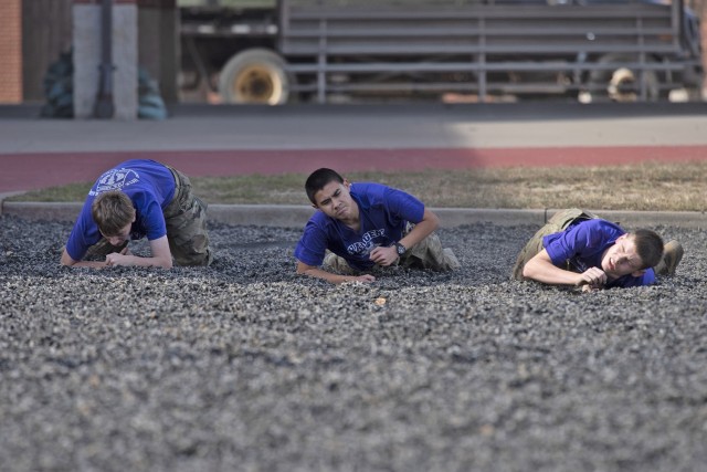 Junior ROTC cadets from Topeka West High School, in Topeka, Kansas, complete the low crawl portion of the physical team tasks event Saturday in the 31st Engineer Battalion training area during the 2022 Raider Challenge competition.