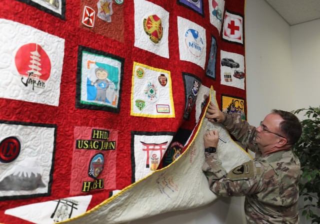 Col. Christopher L. Tomlinson, commander of U.S. Army Garrison Japan, signs a Camp Zama community quilt during a ceremony at Camp Zama, Japan, Nov. 1, 2022. The first-ever community quilt was designed by more than 35 units and private organizations.