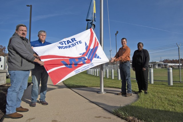 From left: Chemical Defense Training Facility Deputy Director Greg Wolf, CDTF Safety Specialist George Dalgetty, CDTF Director Dan Murray, and CDTF Surety Support Assistant Michele Sanders pose with the Occupational Safety and Health Administration Voluntary Protection Program Star Work Site flag Friday outside the CDTF. OSHA recertified the Fort Leonard Wood facility last month as a VPP Star Work Site – the office’s highest standard for workplace safety. The CDTF, which conducts live chemical warfare agent training for the Department of Defense, received its initial certification in 2019. 