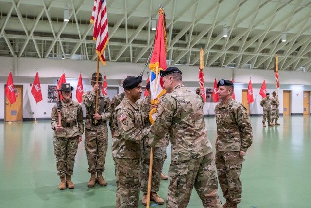Incoming 1st Engineer Brigade Command Sgt. Maj. Don Batchan (left) accepts the brigade guidon from Col. Aaron Bohrer, the brigade commander, as outgoing brigade Command Sgt. Maj. Rodney Russell (right) looks on during a change-of-responsibility ceremony Tuesday at Nutter Field House. 