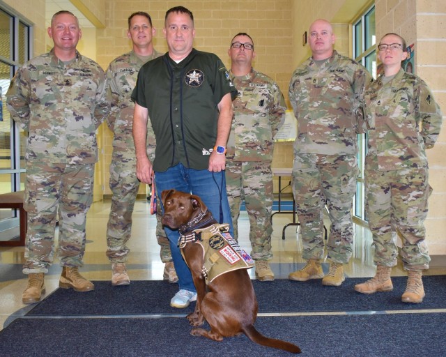 Retired Staff Sgt. Mark Villegas, a former military police officer, and his service dog, Astro, pause for a photo with signal Soldiers from Fort Gordon following a Veterans Day presentation.