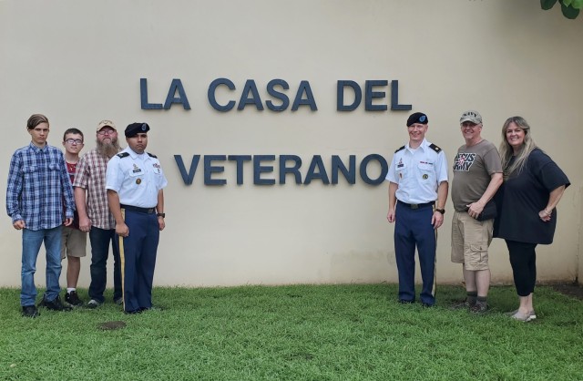(L to R) Fort Buchanan Volunteers, Kelub, Jekub and Joseph Bender; Religious Affairs Noncommissioned Officer, Staff Sgt. Juan Merced Jaipersad; Garrison Command Chaplain Maj. David S. Keller; Fort Buchanan Volunteers US Navy (Ret.) Anthony W. Buie and his spouse Grace Buie pose by the Veteran’s House entrance.