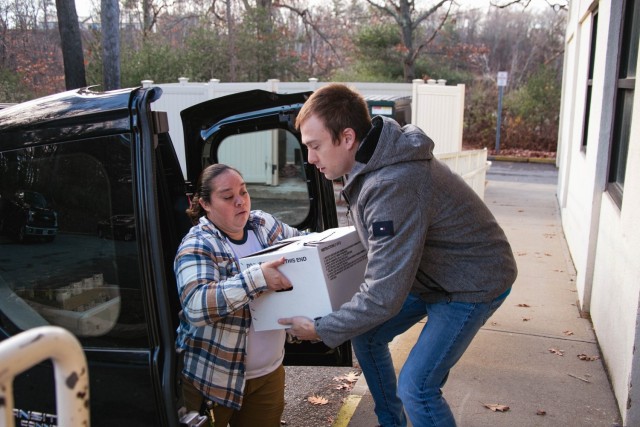 Megan Tetreault hands Zach Desautles a box of food at the food drive drop off. 