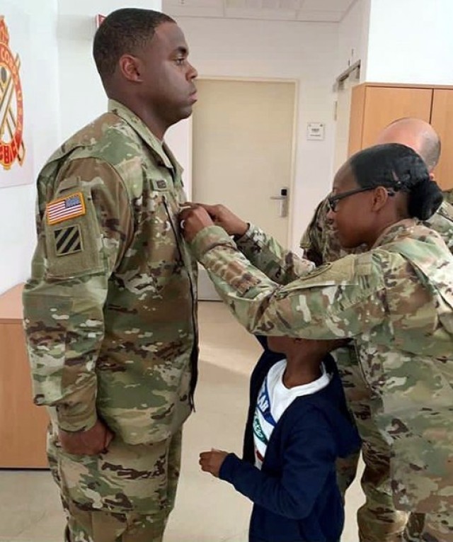 Staff Sgt. Derrick Hodges’ wife, Sgt. 1st Class Angela Hodges, pins on his new rank during a promotion ceremony with the help of their son, Dreveon. (Courtesy photo)