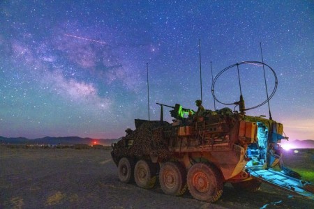 Army Sgt. Justin Covert mans an M1A2 .50-caliber machine gun on a Stryker vehicle during training at Fort Irwin, Calif., as the Milky Way galactic center is visible overhead, May 24, 2022.