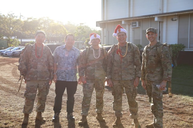 U.S. Army Soldiers from the 3rd Squadron, 4th Cavalry Regiment, 3rd Infantry Brigade Combat Team, 25th Infantry Division pose for a photo with Sam Bennett, the principal of the Ka’Ala Elementary School in Wahiawa, HI, Dec. 1, 2022. The soldiers completed a ruck march to Ka’Ala Elementary School to deliver donated gifts in hopes of supporting the school and children during the holiday season. (U.S. Army photo by Sgt. Katelyn Vazquez/28th Public Affairs Detachment)