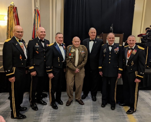 Lockered &#34;Bud&#34; Gahs from Perry Hall, Maryland, who served as a private in the 42nd Infantry Division&#39;s 222nd Infantry Regiment, shared his memories of World War II with 300 New York Army National Guard Soldiers Dec. 2, 2022, in Albany, New York. Left to right, Maj. Gen. Thomas Spencer, commanding general, 42nd Infantry Division, and former CGs: Brig. Gen. Paul Genereux, Maj. Gen. Harry Miller, Maj. Thomas Kinley, Maj. Gen. Steve Wickstrom, and Maj. Gen. Steve Ferrari. Gahs is in the middle. (Courtesy photo)
