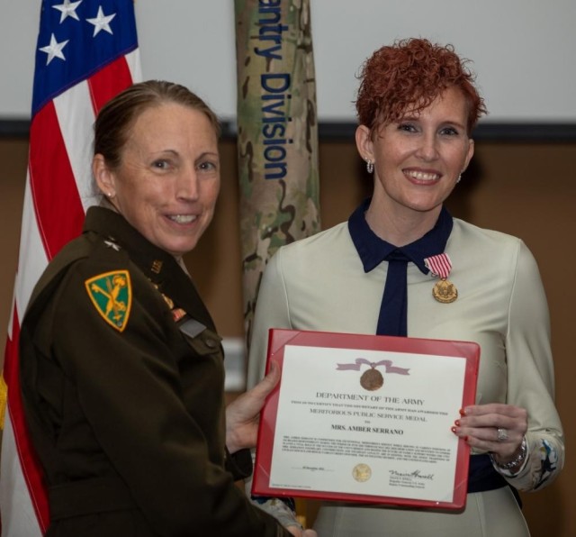 1st Infantry Division Deputy Commanding General-Support, U.S. Army Brig. Gen. Niave F. Knell, presents Amber Serrano, wife of U.S. Army Command Sgt. Maj. Albert Serrano, the outgoing ready reserve command sergeant major for 1st Inf. Div. with the Meritorious Public Service Medal for her service and sacrifice as an Army spouse during a Victory with Honors ceremony held at Victory Hall on Fort Riley, Kansas, Dec. 9, 2022. (U.S. Army Photo by Pfc. Kenneth Barnet)