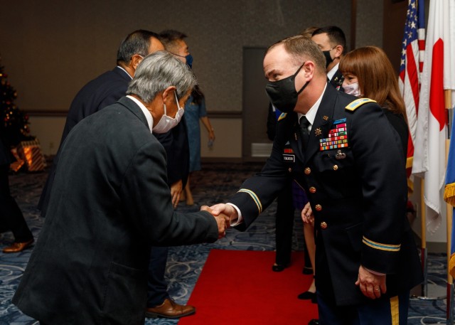 Col. Christopher L. Tomlinson, right, commander of U.S. Army Garrison Japan, greets a Japanese partner during a holiday reception at the Camp Zama Community Club, Japan, Dec. 9, 2022. 