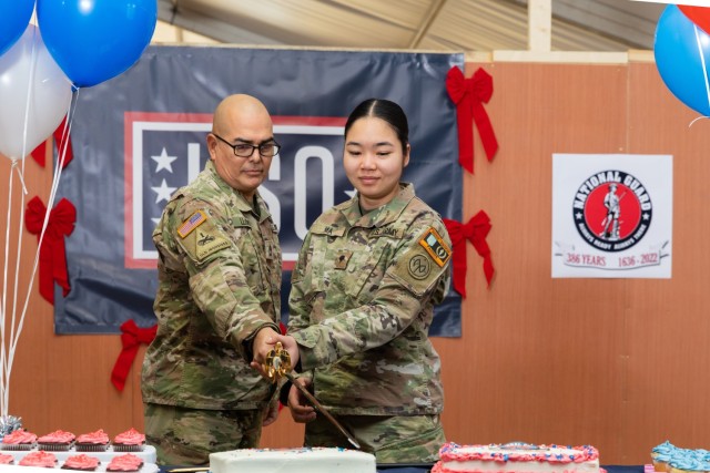 U.S. Army Sgt. 1st Class Raul Llopis, a unit supply specialist, and Spc. Catherina Ma, a combat medic, both assigned to Task Force Orion, 27th Infantry Brigade Combat Team, New York Army National Guard, carry on the Army tradition of a unit’s oldest and youngest Soldiers cutting a cake during a celebration of the 386th National Guard birthday in Grafenwohr, Germany, Dec. 13, 2022. The formation of the first militia regiments in North America on Dec. 13, 1636, is recognized as the birth of the National Guard.