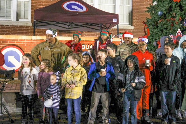 Maj. Gen. Michel M. Russell Sr., commanding general, 1st Theater Sustainment Command, and Command Sgt. Maj. Albert E. Richardson Jr., senior enlisted advisor, 1st TSC, sing holiday songs with children of First Team members at the unit's tree lighting Dec. 9, 2022, in front of Fowler Hall at Fort Knox, Kentucky.