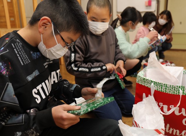 A group of children at the Seikou Gakuen children&#39;s home open presents donated by the Camp Zama community during an outreach event in Zama, Japan, Dec. 21, 2022.