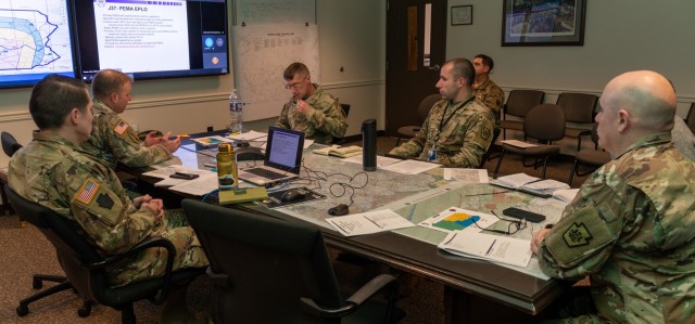 Members of the Pennsylvania National Guard Joint Operations Center staff participate in a conference call, from the Joint Operations Center conference room, with members across the commonwealth as part of a winter storm tabletop exercise designed to improve and validate domestic response procedures on Dec. 20, 2022, at Fort Indiantown Gap, Pa. (This photo was altered to obscure an ID card.)