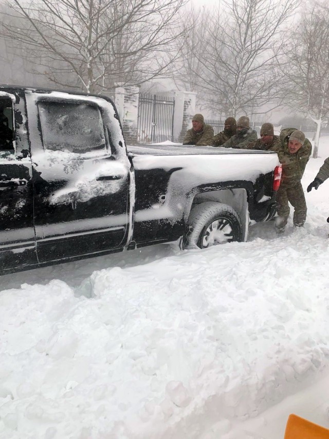 New York Army National Guard Soldiers assigned to the 827th Engineer Company and Airmen assigned to the 174th Attack Wing clear snow to free an AMR ambulance in Buffalo, N.Y., Dec. 26, 2022. Hundreds of New York National Guard members deployed to western New York following the Christmas weekend snowstorm.