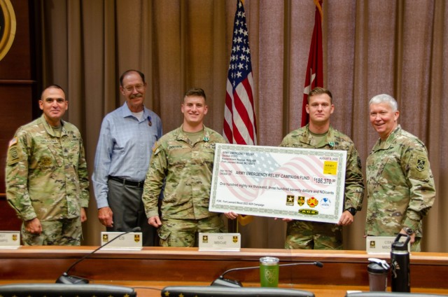 Army Emergency Relief Officer Chuck Matthews and volunteer coordinators 2nd Lt. Jordan Anderson, Company C, 554th Engineer Battalion, and Staff Sgt. Shawn McLain, Company E, 701st Military Police Battalion, present a ceremonial check to Maj. Gen....