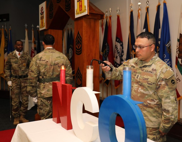 Master Sgt. Roberto Vieyra lights candles on a noncommissioned officer display at the start of an induction ceremony at Sagami General Depot, Japan, Jan. 11, 2023. Twenty NCOs assigned to 35th Combat Sustainment Support Battalion participated in the ceremony.