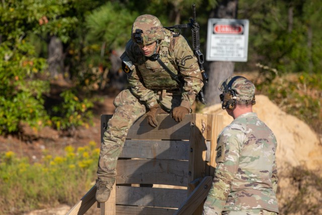 Spc. Nathan J. Wallen of Squad 5, representing the U.S Army Special Operations Command, scales a barrier during the stress shoot portion of the Army Best Squad Competition on Fort Bragg, North Carolina, Oct. 5, 2022. The week-long competition will assess each squad on their technical and tactical proficiency, as well as their ability to work as a disciplined and cohesive team, featuring a multitude of fitness, knowledge and combat-related events.