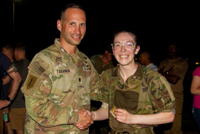 U.S. Army Lt. Col. Shawn Tabankin, commander of 1st Battalion, 69th Infantry Regiment, presents a challenge coin to Capt. Nina Skinner, a communications officer with 1st Battalion, 69th Infantry Regiment, after she completed a Norwegian Foot March at Camp Lemonnier, Djibouti, Dec. 16, 2022. Skinner received the coin for placing first among female participants with a finish time of 3 hours and 59 minutes.