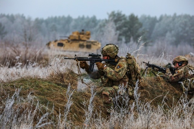 U.S. Soldiers assigned to Chaos Company, 3rd Battalion, 8th Cavalry Regiment, 3rd Armored Brigade Combat Team, 1st Cavalry Division (3-1 ABCT) operationally controlled by the 1st Infantry Division (1 ID), advance on the target with fire support from a M2A3 Bradley Fighting Vehicle during the Bull Run live fire exercise in Bemowo Piskie, Poland, Nov. 23, 2022. The 3-1 ABCT is among other units assigned to the 1 ID, proudly working alongside NATO allies and regional security partners to provide combat-credible forces to V Corps, America's forward deployed corps in Europe. (U.S. Army National Guard photo by Staff Sgt. Matthew A. Foster)