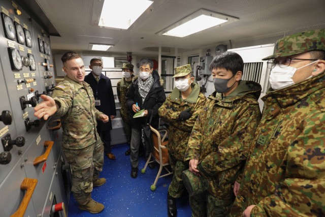 Staff Sgt. Robert Marsh, left, assistant chief engineer of LCU Calaboza, shows the engine room to a group of Japan Ground Self-Defense Force leaders during a tour of the U.S. Army landing craft utility vessel at Yokohama North Dock, Japan, Jan. 25, 2023.