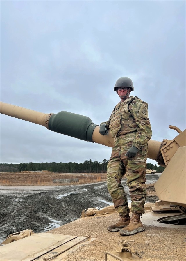 Pvt. 1st Class Kristie Hawley poses with the 120mm cannon of an M1A2 Abrams Main Battle Tank