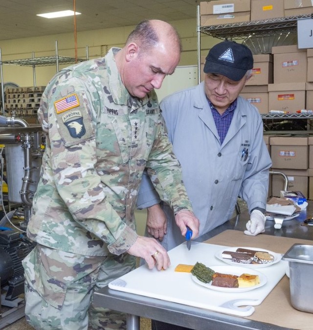 General Andrew P. Poppas, Commanding General of U.S. Army Forces Command (FORSCOM), tries prototype ration samples developed through Vacuum Microwave Drying Technology by Dr. Tom Yang, a senior food technologist with the Combat Feeding Division, during a January 25 visit to the U.S. Army Combat Capabilities Development Command (DEVCOM) Soldier Center in Natick, Massachusetts.