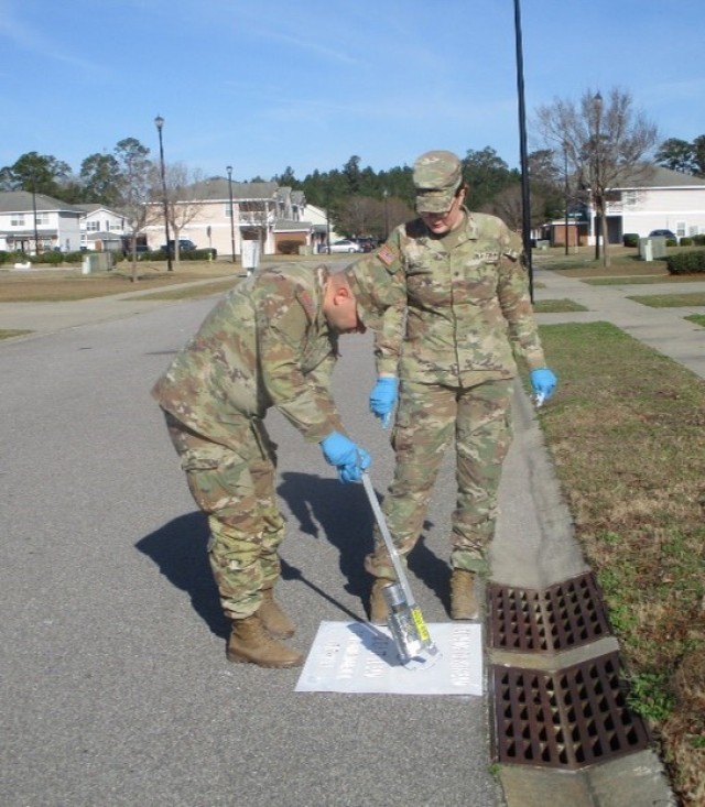 Sgt. Mykola Iudin and Spc. Taryn Housley, 63rd Expeditionary Support Battalion, 3rd Sustainment Brigade paint messages on storm drains in the Liberty Woods housing area, Feb. 7 on Fort Stewart, Georgia. 