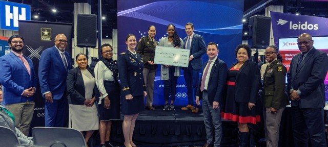 The xTechHBCU Student Competition’s third place winner (center), Shirley Jacquet, being presented with her cash prize by Dr. Matt Willis (stage center right), director, and LTC Sherida Whindleton (stage center left), deputy director, of Army...