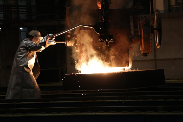 An employee wears a protective uniform as they conduct a foundry pour at Rock Island Arsenal-Joint Manufacturing and Technology Center (JMTC photo)