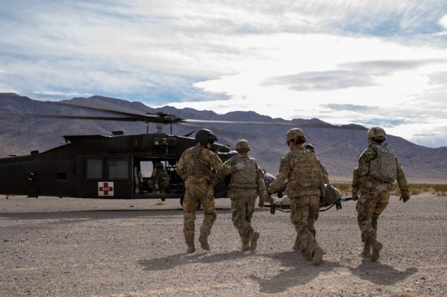 U.S. Army Soldiers assigned to 1st Squadron, 7th Cavalry Regiment, 1st Armored Brigade Combat Team carry a casualty to a Black Hawk during Project Convergence 2022 at Fort Irwin, Calif., Nov. 7, 2022.