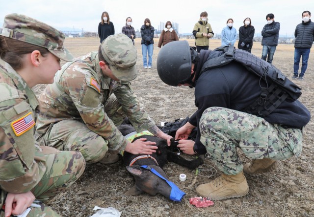 Sgt. Madison Green, left, an animal care specialist, evaluates how military dog handlers treat wounds on a life-like animatronic dog during a K-9 tactical combat casualty care exercise at Sagami General Depot, Japan, Feb. 24, 2023.