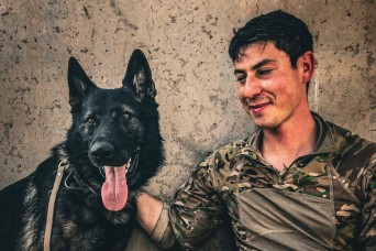 Army Explosive Ordnance Disposal officer bonds with Navy working dog on battlefield