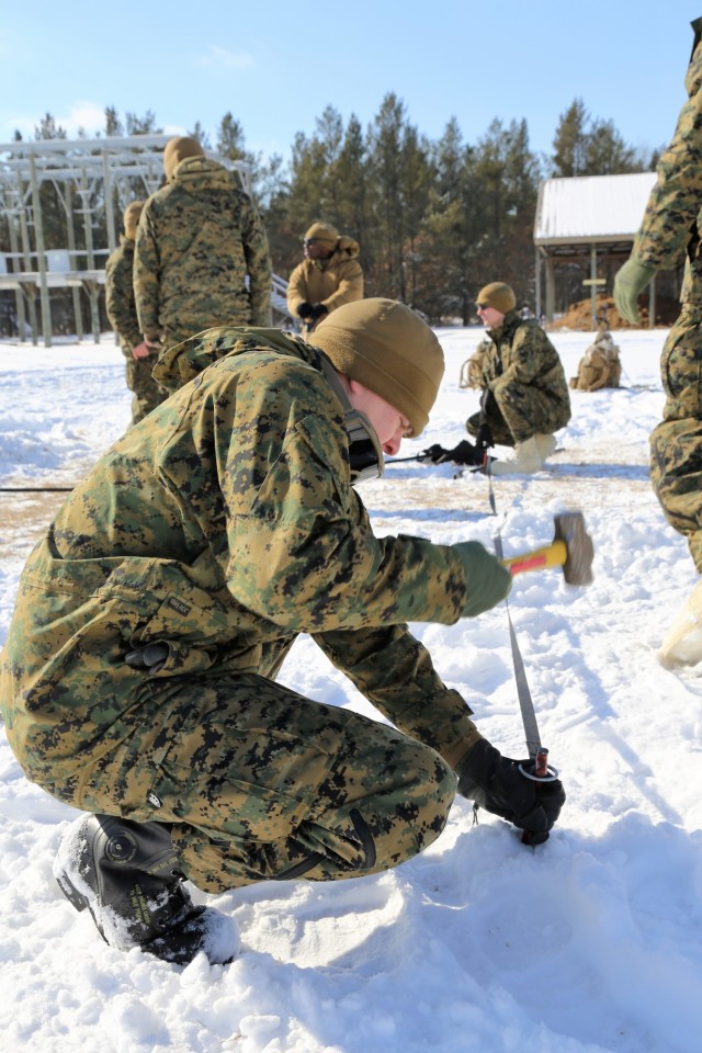 A Marine who was a student in the Cold-Weather Operations Course (CWOC) Class 18-04 pounds a tent stake into the ground during training on building an Arctic 10-person tent as part of the course Feb. 7, 2018, at Fort McCoy, Wis. The students included Marines and Soldiers. In addition to tent building, CWOC students are trained on a variety of cold-weather subjects, including snowshoe training and skiing as well as how to use ahkio sleds and other gear. Training also focuses on terrain and weather analysis, risk management, cold-weather clothing, developing winter fighting positions in the field, camouflage and concealment, and numerous other areas that are important to know in order to survive and operate in a cold-weather environment. The training is coordinated through the Directorate of Plans, Training, Mobilization and Security at Fort McCoy. (U.S. Army Photo by Scott T. Sturkol, Public Affairs Office, Fort McCoy, Wis.)