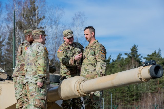 U.S. Army Staff Sgt. Angelo E. Gelster, an ammunition specialist assigned to Task Force Orion, 27th Infantry Brigade Combat Team, New York Army National Guard, is promoted during a ceremony atop an M1A2 Abrams tank in Grafenwoehr, Germany, Feb. 20, 2023. Gelster, a former armor crewmember who operated M1A1 Abrams tanks with the now-disbanded 127th Armor Regiment, is deployed to Germany in support of the Joint Multinational Training Group – Ukraine mission to ensure the combat effectiveness of Ukrainian military personnel training in Germany. (U.S. National Guard photo by Staff Sgt. Jordan Sivayavirojna)