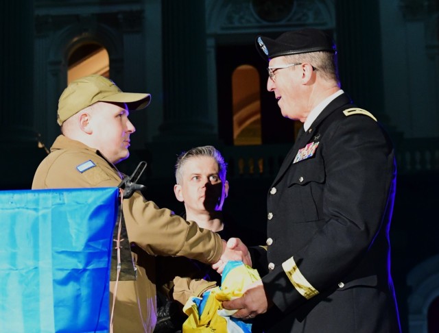 A double-amputee Ukrainian soldier presents a Ukrainian flag signed by fellow Ukrainian soldiers to Maj. Gen. Matthew P. Beevers, acting adjutant general of the California National Guard, in Sacramento, California, Feb. 24, 2023. (U.S. Army National Guard photo by Amanda H. Johnson)