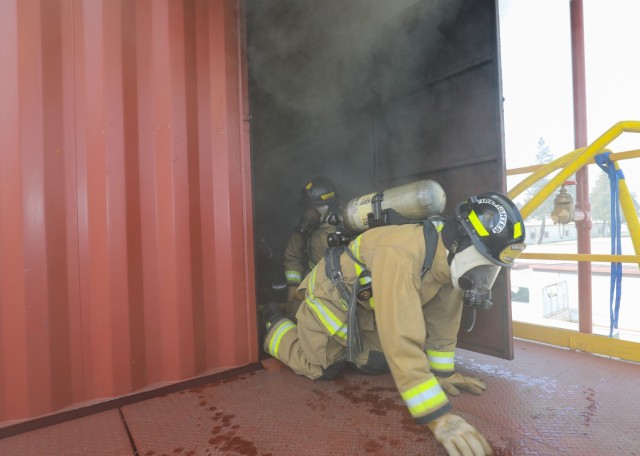 U.S. Army Garrison Japan firefighters crawl under the smoke during a live-fire scenario inside a new training facility at Sagami General Depot, Japan, March 9, 2023. After being trained by contractors on the facility earlier this year, the USAG Japan fire department has recently begun to train its own personnel on the proper ways to handle indoor fires.