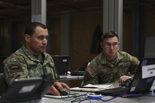 U.S. Army Sgt. Jordan Cearlock, V Corps Battalion NCO, assists Lithuanian Lt. Col. Vadimas Jeriominas, Lithuanian National Command Element Liaison Officer, V Corps, during the Joint Multinational Simulation Center hosted, Allied Spirit 23 Command Post Exercise 1 for U.S. forces and multinational partners on March 7, 2023 on Camp Aachen at the Grafenwoehr Training Area, Germany. The Allied Spirit CPX 1 is a command post exercise for V Corps with participation of two multinational division elements, the Polish 12th Mechanized Division and Lithuanian Mission Command Element, in preparation for the corps’ Warfighter Exercise (WFX).