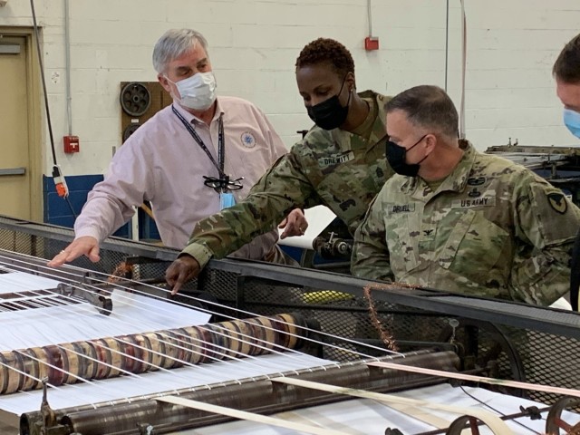 (From left) Blind Industries and Services of Maryland President Fred Puente shows APG Garrison Command Sgt. Maj. Ruth Drewitt and APG Garrison Commander Col. Timothy Druell a machine for ruling pape
