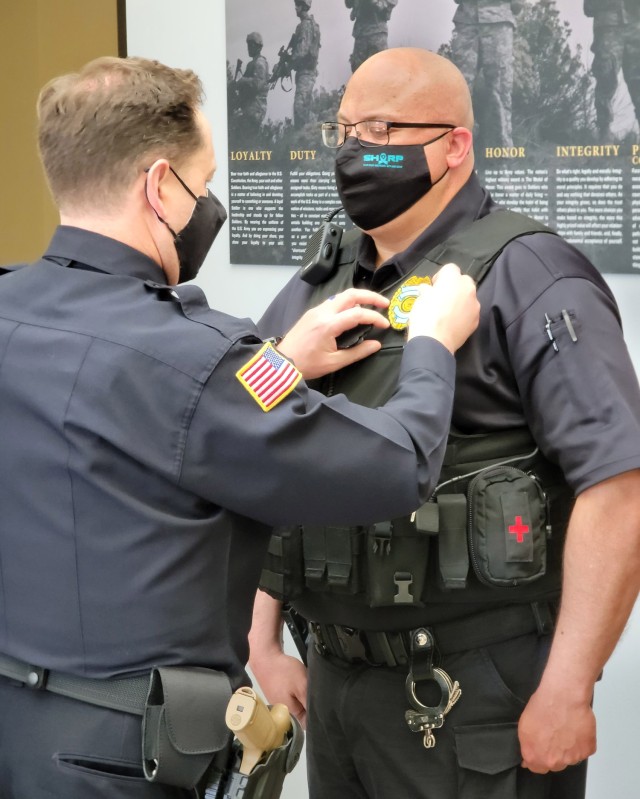 Chief of Police Joel Holdford presents a teal badge to Police Officer Sgt. Timothy Knight, with the Directorate of Operations