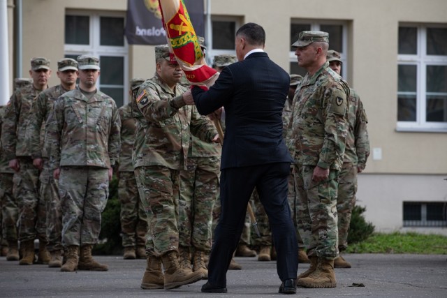 U.S. Army Col. Jorge M. Fonseca, the commander of United States Army Garrison Poland, receives the colors from Mr. Tommy R. Mize, the director of Installation Management Command-Europe, during an assumption of command ceremony in Camp Kosciuszko, Poland, March 21, 2023. The establishment of the U.S. Army&#39;s enduring presence in Poland demonstrates the United States&#39; commitment to the Republic of Poland, the NATO Alliance and to the support of mission partners.
