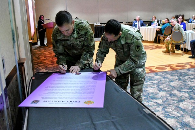 Maj. Gen. Gregory Anderson, 10th Mountain Division (LI) and Fort Drum commander, and Col. James Zacchino Jr., Fort Drum garrison commander, sign the Month of the Military Child Proclamation on March 21 during the Fort Drum Educational Liaison...