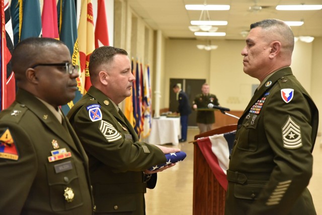 Sgt. Maj. Jon Greer, First U.S Army, receives a U.S. flag from Sgt. Maj. Timothy Jensen, U.S. Army Sustainment Command, G-3 Operations, during the quarterly retirement ceremony at Rock Island Arsenal, Illinois, March 7. 