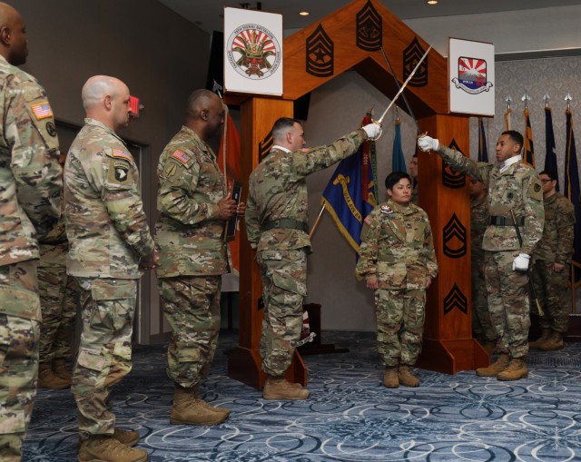 Sgt. Jeymi Rodriquez-Sanchez, assigned to U.S. Army Aviation Battalion Japan, walks under a wooden arch and a pair of raised sabers to symbolize her entry into the NCO corps during a ceremony at the Camp Zama Community Club, Japan, March 22, 2023. Nearly 20 noncommissioned officers participated in the ceremony, which was hosted by the 78th Signal Battalion and USAABJ.