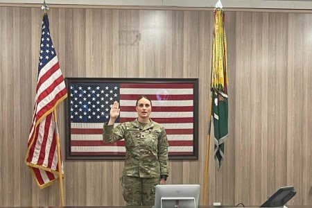 SPC Dakota Anderson looks at a big screen video teleconference system in Iraq as her uncle COL Ronnie Anderson administers her reenlistment oath from Redstone Arsenal, Ala. 